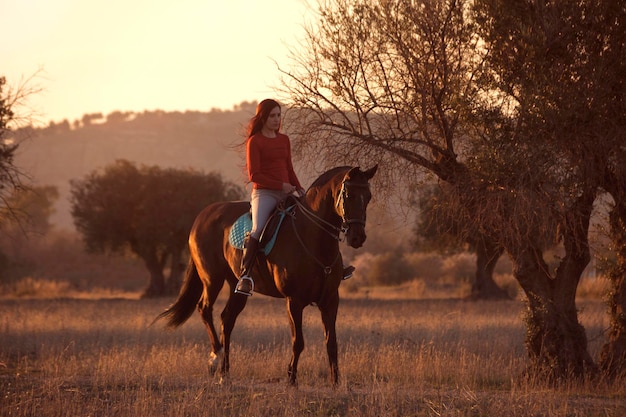 Jovem andando a cavalo em belas paisagens naturais ao pôr do sol