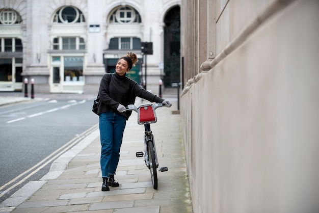 Foto jovem andando com sua bicicleta na cidade