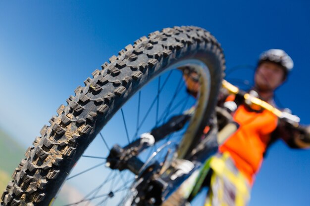 Jovem andando de bicicleta ao ar livre. roda de bicicleta em close-up