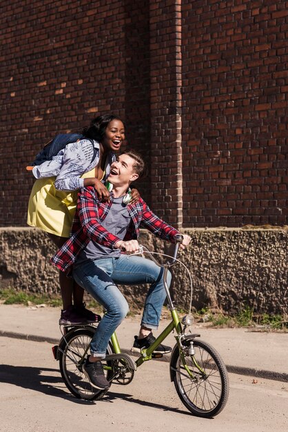 Foto jovem andando de bicicleta com a namorada em pé no rack