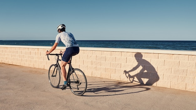 Jovem andando de bicicleta com vista para o mar