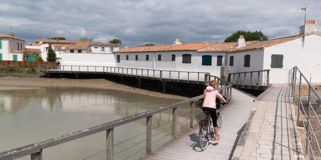 Jovem andando de bicicleta em um caminho de madeira para a praia no dia ensolarado de verão na ilha ile de Re na França