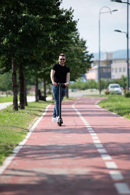 Jovem andando de scooter elétrica no verão na rua