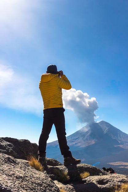 Jovem andando na montanha iztaccihuatl ao amanhecer ao fundo do vulcão popocatepetl