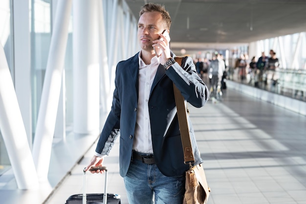 Jovem andando pelo portão do aeroporto e falando ao telefone