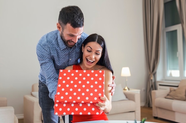 Jovem animada abrindo uma caixa de presente recebendo um bom presente inesperado do marido