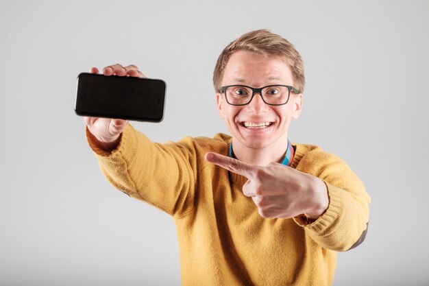 Jovem animado mostrando a tela em branco de seu smartphone móvel