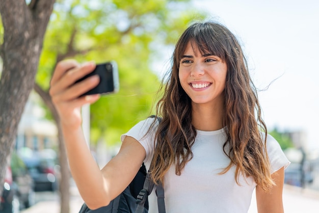 Jovem ao ar livre fazendo uma selfie