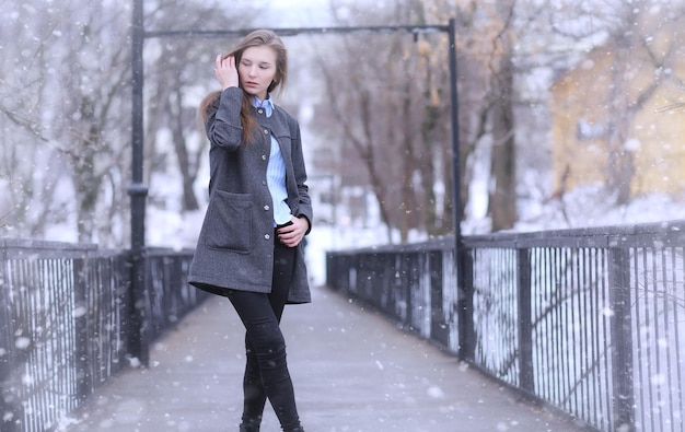 Jovem ao ar livre no inverno. Menina modelo posando ao ar livre em um dia de inverno. Fim de semana festivo na garota andando de rua.