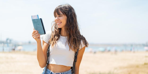 Jovem ao ar livre segurando um passaporte com expressão feliz