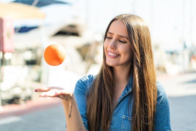 Jovem ao ar livre segurando uma laranja