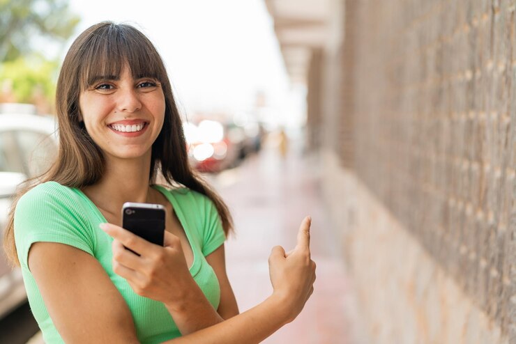 Foto jovem ao ar livre usando telefone celular e apontando para trás
