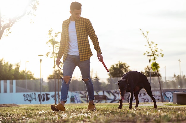 Foto jovem apaixonado com seu cachorro andando no parque.