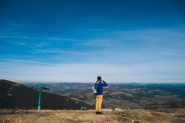 Jovem apontando em uma pedra, curtindo a vista