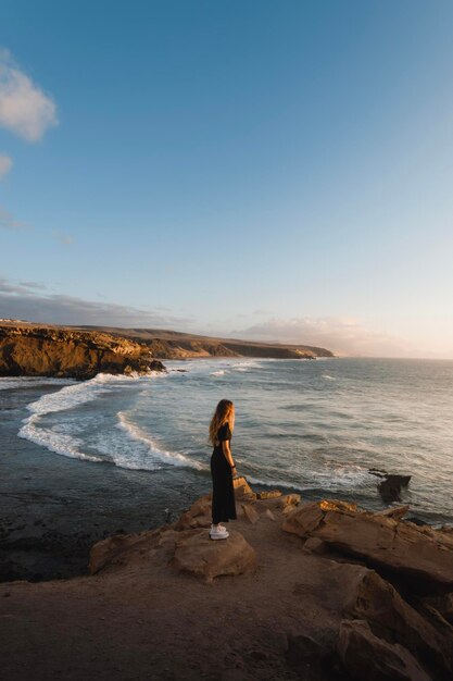 Jovem aprecia o pôr do sol na costa de Fuerteventura enquanto visita as Ilhas Canárias