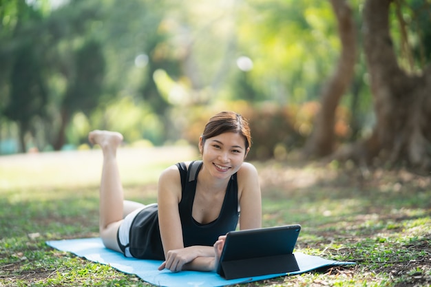 Jovem aprendendo exercícios de ioga em uma videoconferência ao ar livre no parque