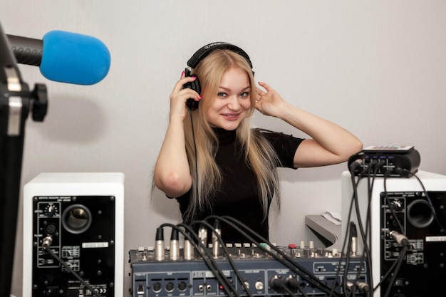 Jovem apresentadora de rádio DJ em estúdio com microfone de fones de ouvido soa console misto e fala notícias ao vivo