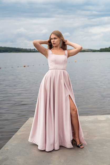 Jovem, aproveitando o verão, posando sozinha com um lindo vestido ping perto do lago, estilo de vida