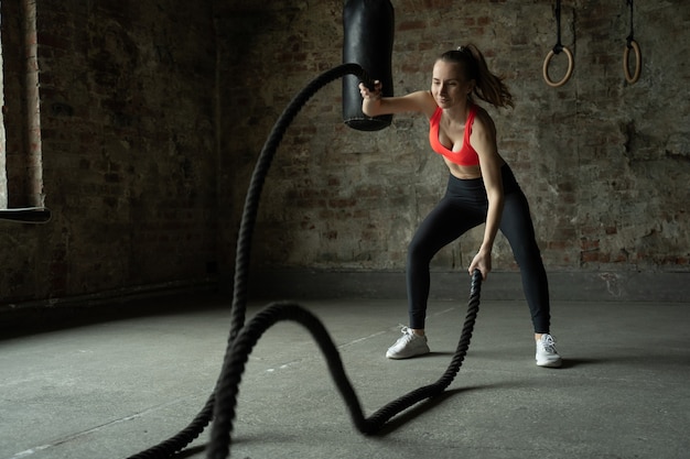 Jovem apto desportista a exercitar-se no ginásio de treino de fitness.