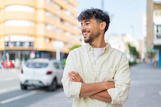 Jovem árabe bonito ao ar livre feliz e sorridente