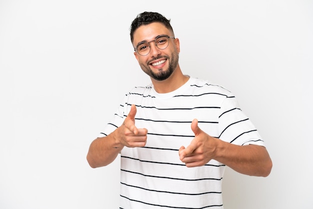 Jovem árabe bonito isolado no fundo branco, apontando para a frente e sorrindo