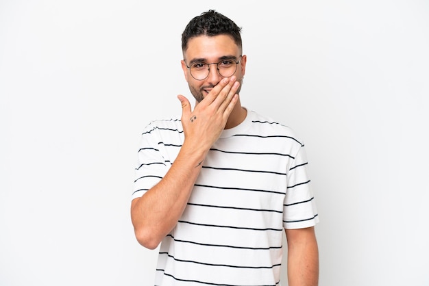 Jovem árabe bonito isolado no fundo branco feliz e sorridente cobrindo a boca com a mão