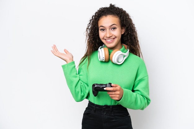 Jovem árabe brincando com um controlador de videogame isolado no fundo branco, estendendo as mãos para o lado para convidar para vir