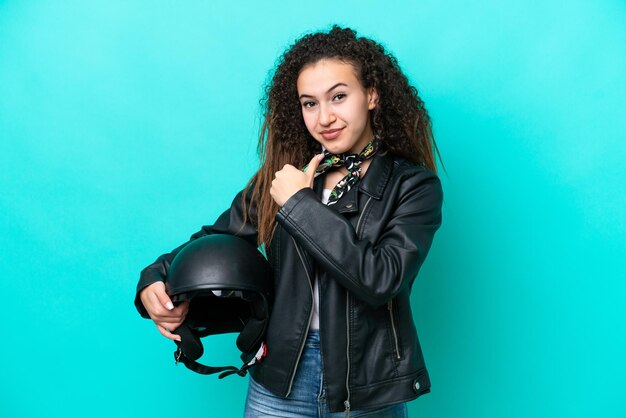 Jovem árabe com um capacete de motocicleta isolado em fundo azul orgulhoso e satisfeito