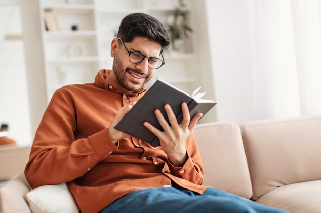 Jovem árabe de óculos lendo livro