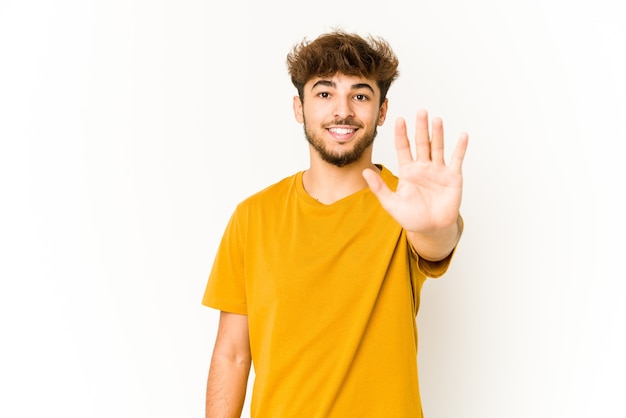 Jovem árabe em branco sorrindo alegre mostrando o número cinco com os dedos.