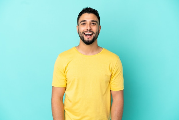 Jovem árabe isolado em um fundo azul com expressão facial surpresa