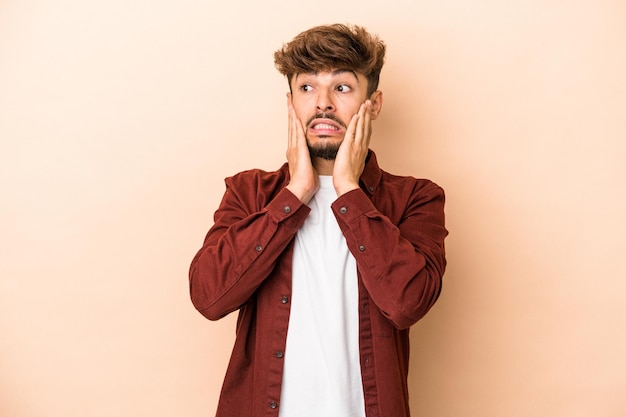 Jovem árabe isolado em um fundo bege com medo e medo.