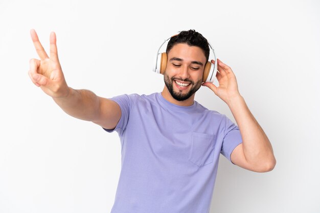 Jovem árabe isolado em um fundo branco ouvindo música e cantando