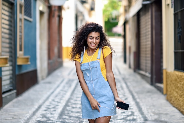 Jovem, árabe, mulher, escutar música, com, fones ouvido, ao ar livre