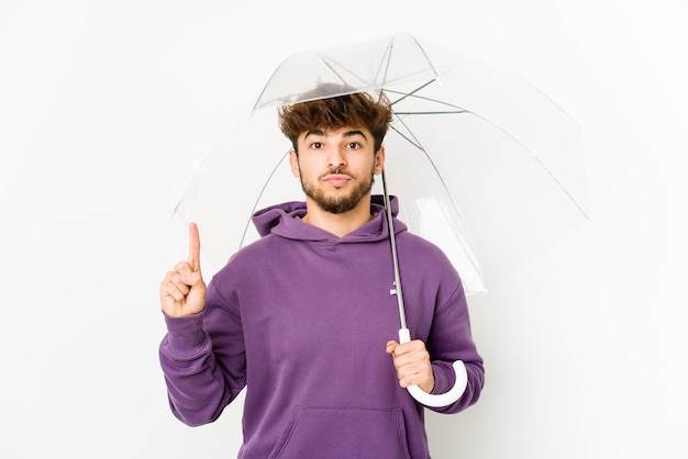 Jovem árabe segurando um guarda-chuva, mostrando o número um com o dedo.