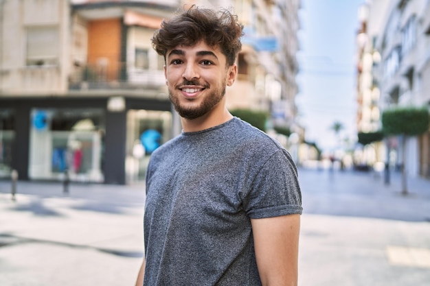 Jovem árabe sorrindo feliz em pé na cidade