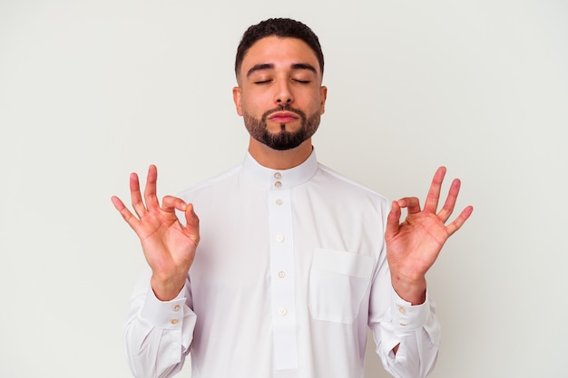 Jovem árabe vestindo roupas típicas árabes, isoladas no fundo branco relaxa após um árduo dia de trabalho, ela está realizando ioga.