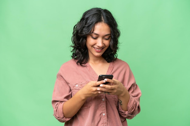 Jovem argentina sobre fundo isolado, enviando uma mensagem com o celular