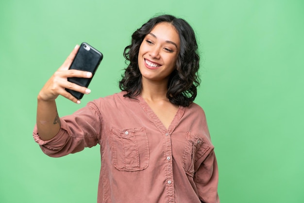 Jovem argentina sobre fundo isolado fazendo uma selfie