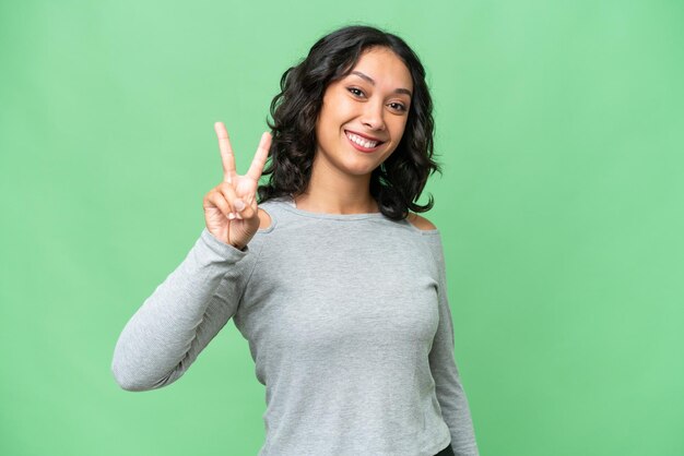 Jovem argentina sobre fundo isolado, sorrindo e mostrando sinal de vitória