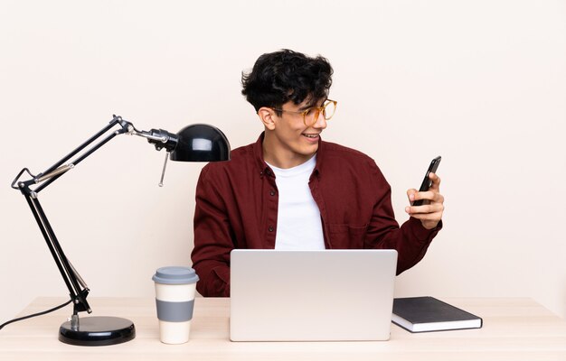 Jovem argentino em uma mesa com um laptop em seu local de trabalho