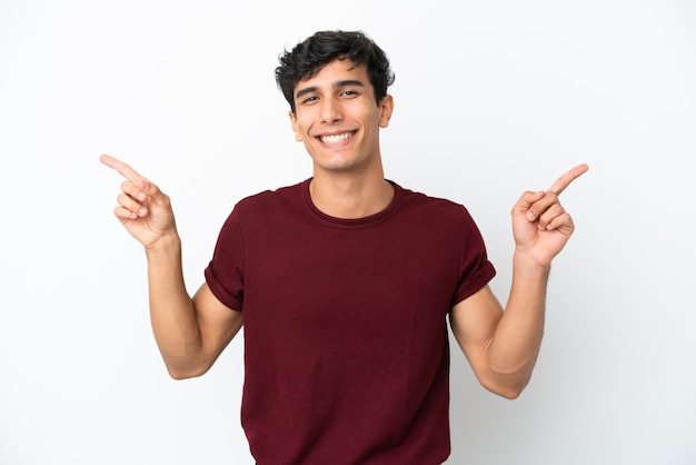 Jovem argentino isolado em fundo branco apontando o dedo para as laterais e feliz