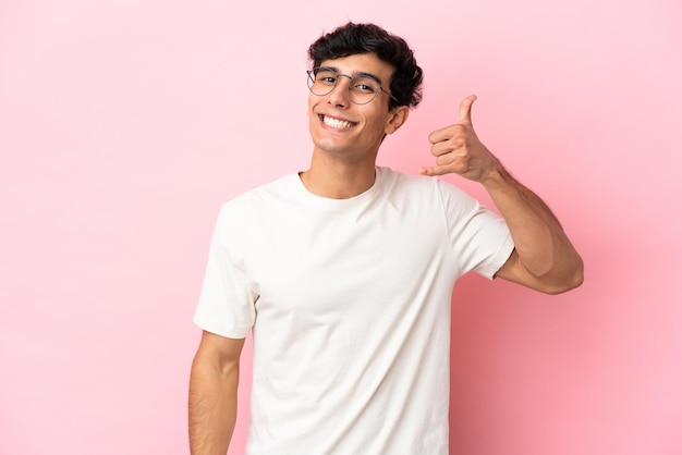 Jovem argentino isolado em fundo rosa fazendo gesto de telefone Ligue-me de volta sinal