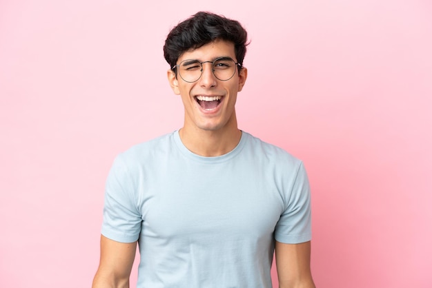 Jovem argentino isolado em um fundo rosa Com óculos e uma expressão feliz