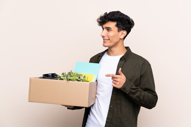 Jovem argentino movendo-se em nova casa sobre isolado apontando para o lado para apresentar um produto