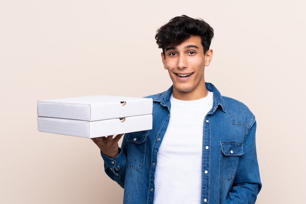 Jovem argentino segurando pizzas sobre parede isolada com surpresa e expressão facial chocado