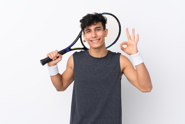 Jovem argentino sobre parede branca isolada, jogando tênis e fazendo sinal de ok