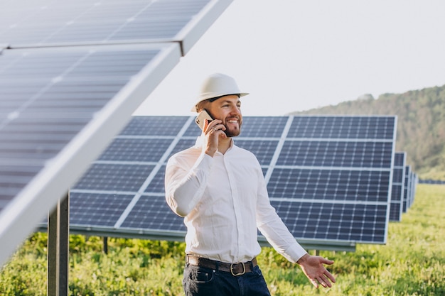 Jovem arquiteto ao lado de painéis solares falando ao telefone