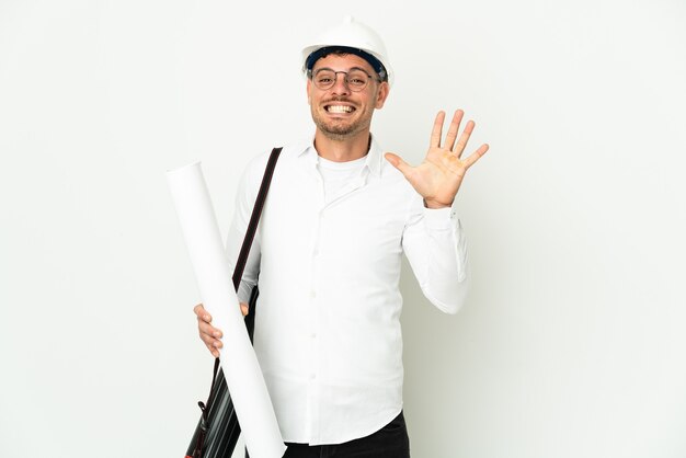 Jovem arquiteto com capacete e segurando plantas isoladas no fundo branco, contando cinco com os dedos