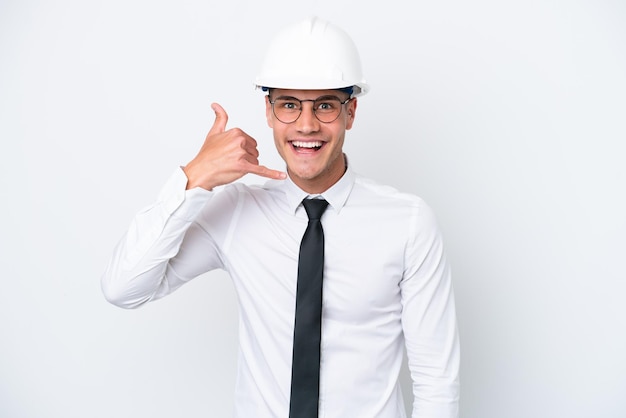 Jovem arquiteto homem caucasiano com capacete e segurando plantas isoladas no fundo branco, fazendo gesto de telefone, ligue-me de volta